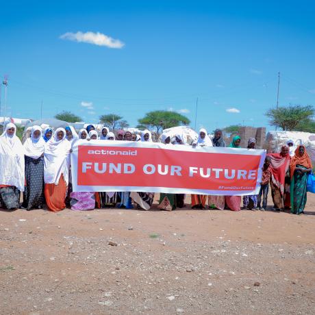 Women hold a banner saying fund our future. 